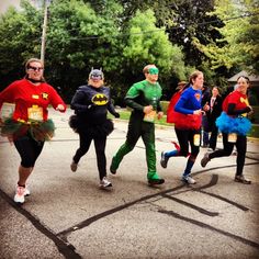 a group of people in costumes running down a street together with trees in the background