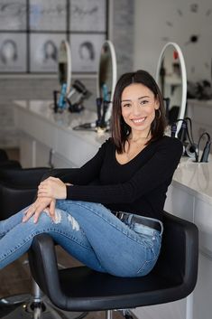 a woman sitting on a chair in front of a hair salon counter with her legs crossed