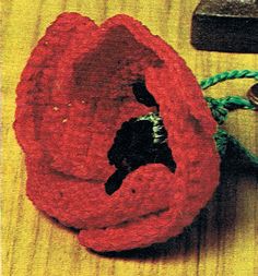 a red flower sitting on top of a wooden table next to an old pair of scissors