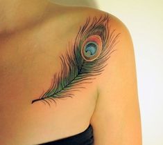 a woman's chest with a peacock feather tattoo on it