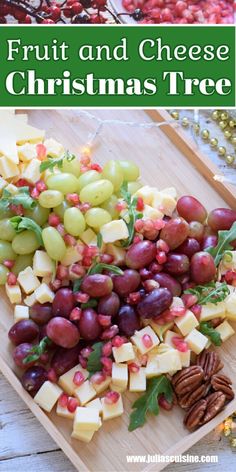 fruit and cheese christmas tree is displayed on a cutting board with pecans, grapes, nuts