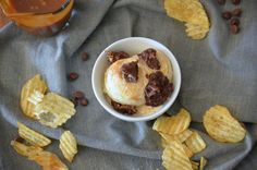 a bowl filled with ice cream and chocolate chips on top of a gray cloth next to a glass of orange juice