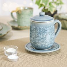 a blue tea pot sitting on top of a plate next to a cup and saucer