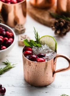 two copper mugs filled with cranberry punch and garnished with fresh greenery