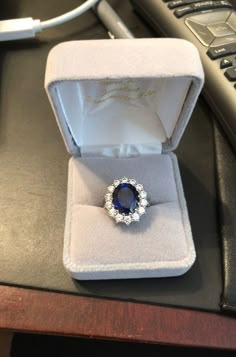 an engagement ring with a blue stone in it sits on a table next to a keyboard