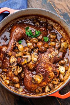 a pot filled with meat and mushrooms on top of a wooden table