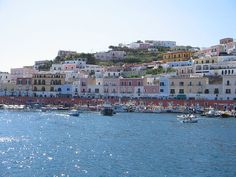 many boats are in the water near some buildings on top of a hill that overlooks a city