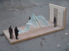 two men are standing in front of an iceberg on the ground and one man is looking at it