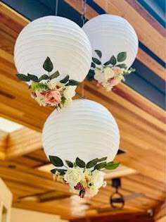 three white paper lanterns with flowers hanging from them