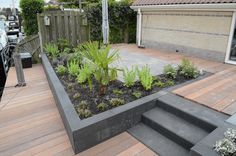 a wooden deck with steps leading up to a small garden area on top of it