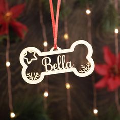 a dog bone ornament hanging from a christmas tree with poinsettis