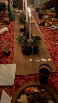 people sitting at a table with food and candles