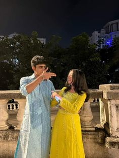 a man and woman standing next to each other in front of a building at night