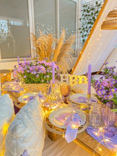 the table is set with purple flowers and candles