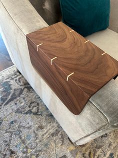 a wooden table sitting on the back of a couch in a living room next to pillows