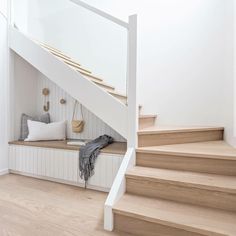 a white staircase with wooden steps leading up to the second floor and storage space below