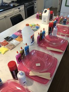 the table is covered with pink plates and craft supplies