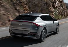 the rear end of a silver suv driving down a mountain road