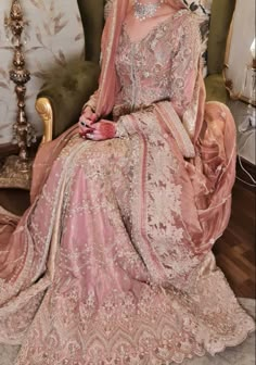 a woman sitting on top of a chair wearing a pink dress and headpieces