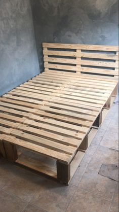 a bed made out of wooden pallets in a room with tile flooring and walls