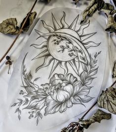 a drawing of the sun and moon on a plate with leaves around it, surrounded by dried flowers