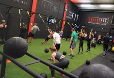 a group of people in a gym doing exercises on exercise balls and pull ups with barbells