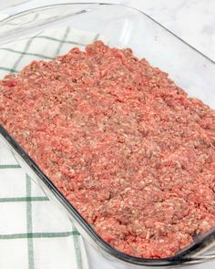 ground beef in a glass casserole dish on a green and white towel