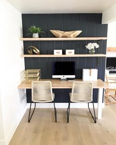 two chairs sit in front of a desk with a computer on it and shelves above the desk