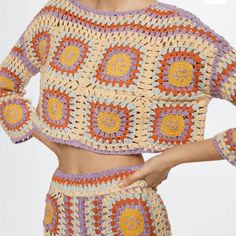 a woman wearing a crocheted crop top and matching shorts with her hands on her hips