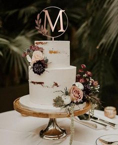 a white wedding cake sitting on top of a table next to silverware and candles