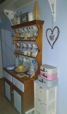 an old china cabinet with dishes on it and other items in the back ground next to it