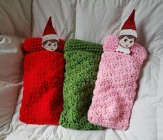 three crocheted sleeping bags with elf faces on them