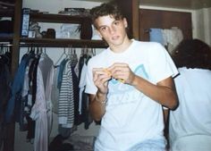 a young man is looking at his watch in front of the closet full of clothes