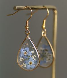 a pair of earrings with flowers hanging from them