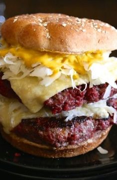 a cheeseburger with meat and onions on a black plate