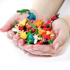 two hands are holding small toy animals in their palms, and one hand is full of them