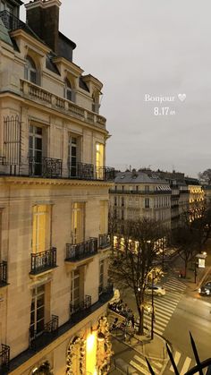 an apartment building with balconies lit up in the evening time, overlooking a street