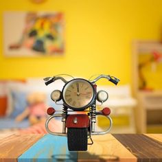 a small motorcycle clock sitting on top of a wooden table next to a child's bed