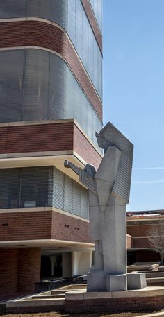 a statue in front of a building with a large window on it's side