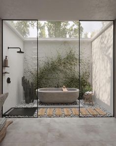 a bathroom with a large bathtub next to a glass wall that has plants growing on it