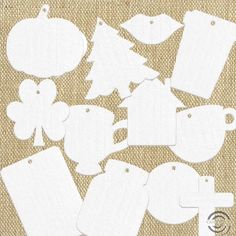 paper cutouts are arranged on a burlap background with white tags and ornaments