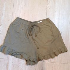 Army Green Color. Stretch Waist With Drawstring. Side Pockets. Ruffled Bottoms. Casual Cotton Ruffle Shorts, Ruffled Shorts For Beach Season, Ruffled Beach Season Shorts, Beach Season Ruffled Shorts, Casual Green Shorts With Ruffles, Casual Green Ruffled Shorts, Green Ruffled Shorts For Summer, Casual Ruffled Bottoms For Beach Season, Casual Ruffled Shorts