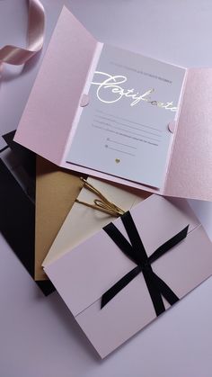 an open pink and black wedding card with a bow on it's front pocket