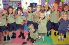 a group of young children standing next to each other in front of a classroom wall