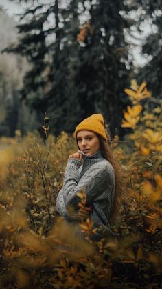 a woman standing in the middle of a field with her hands on her face and wearing a yellow hat