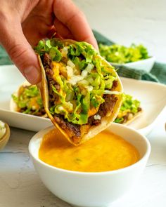 a person dipping sauce into a tortilla filled with meat and veggies