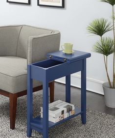 a blue end table with a magazine rack on it and a chair in the background