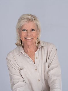 an older woman with blonde hair smiling at the camera while wearing a button up shirt