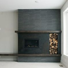 an empty room with a fire place in the center and wood stacked on top of each other