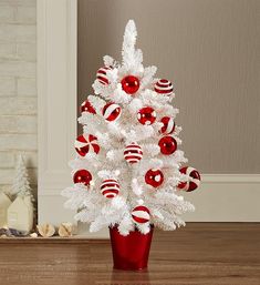 a white christmas tree decorated with red and white bauble ornaments in a vase